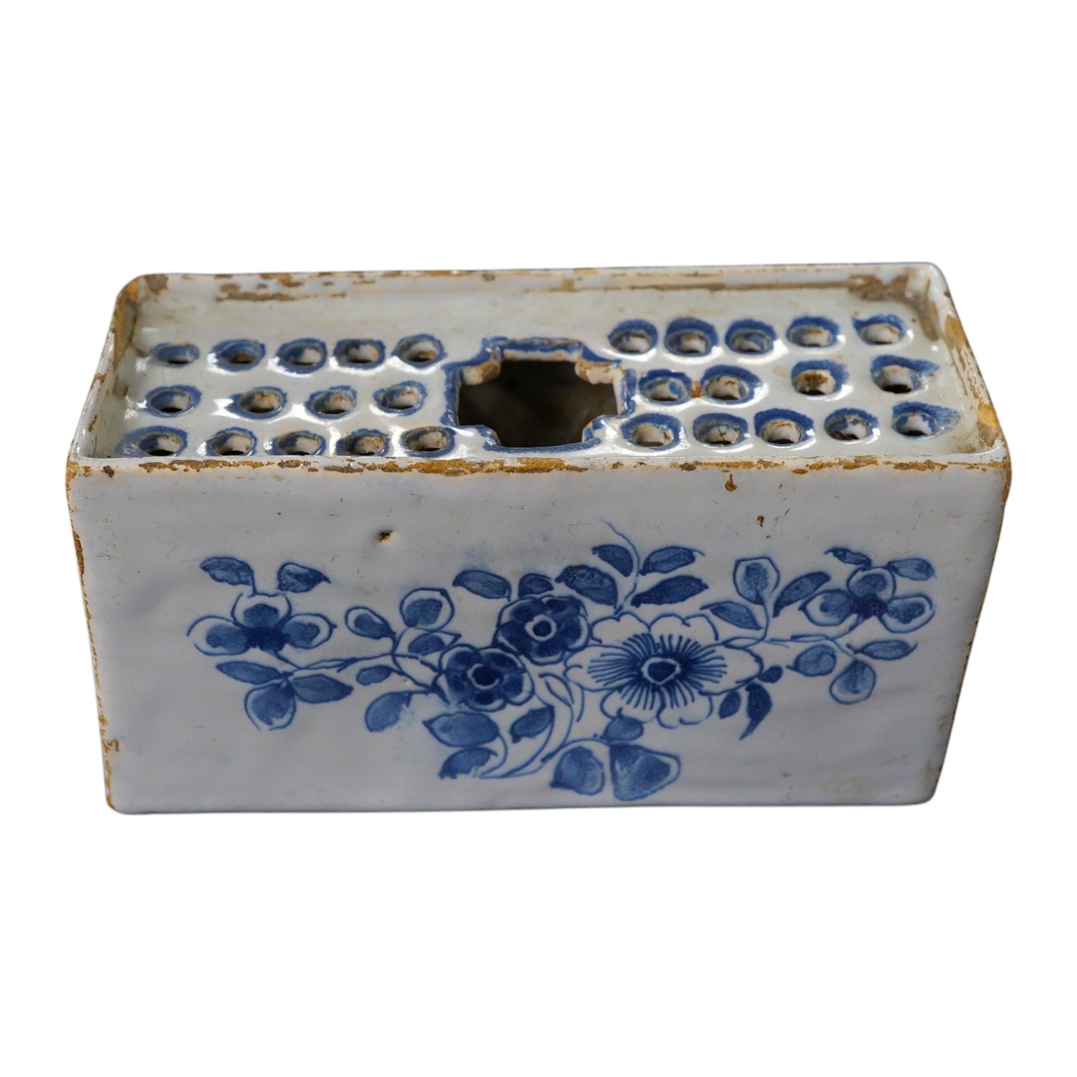 An 18th century English delftware flower brick, 15cm wide, 8cm high. Condition - edges chipped and larger chip to one corner, usual for pottery type, use and age